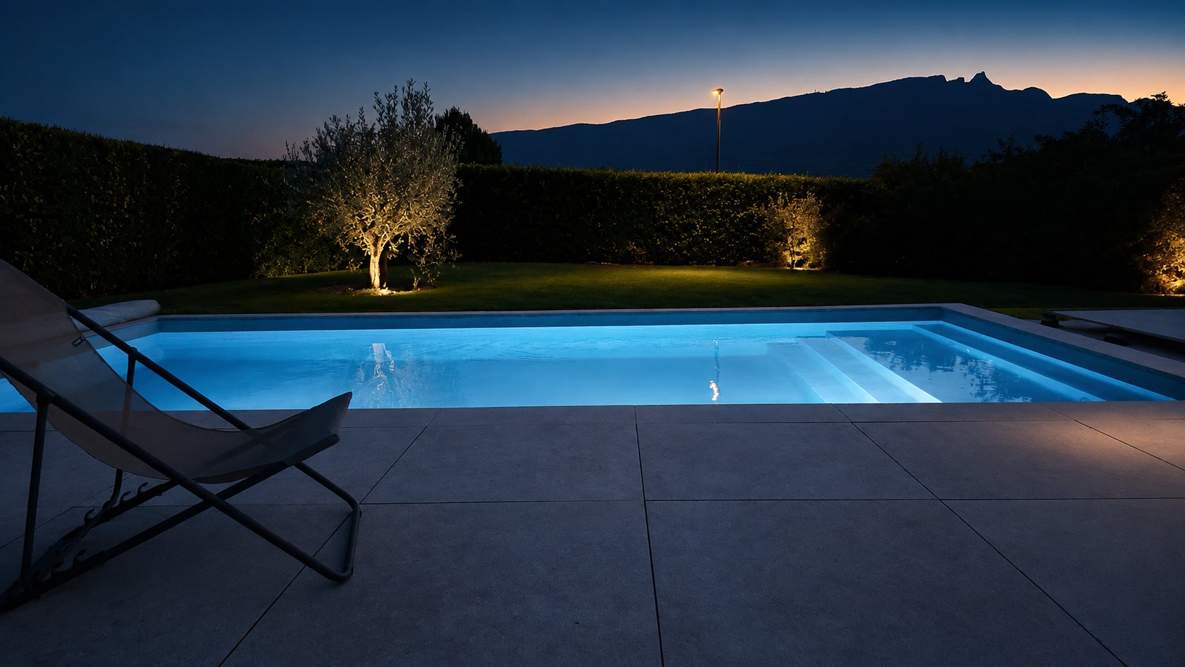Piscine contemporaine éclairée au crépuscule avec vue montagne