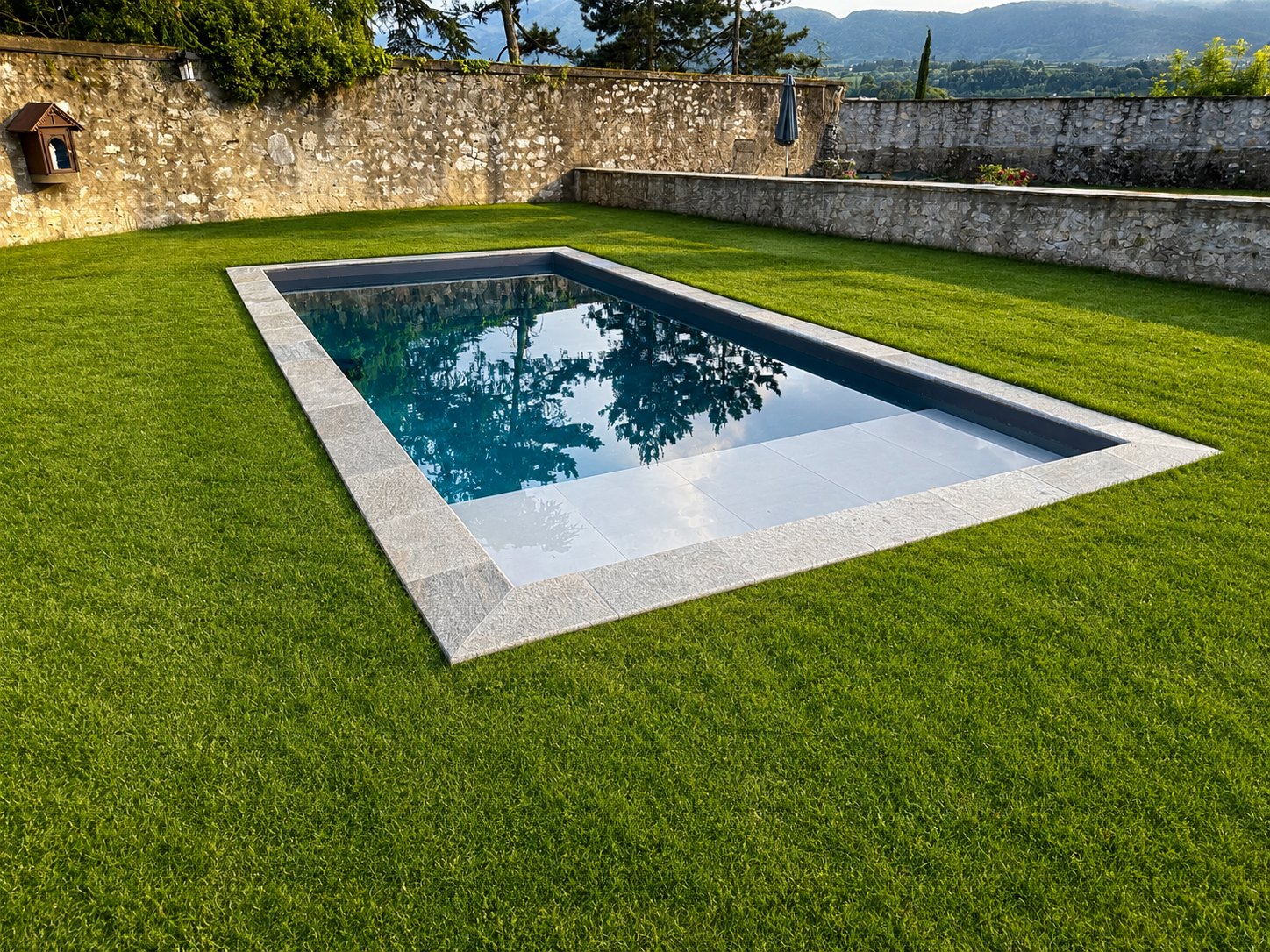 Piscine intégrée dans un jardin ceint de murs en pierre